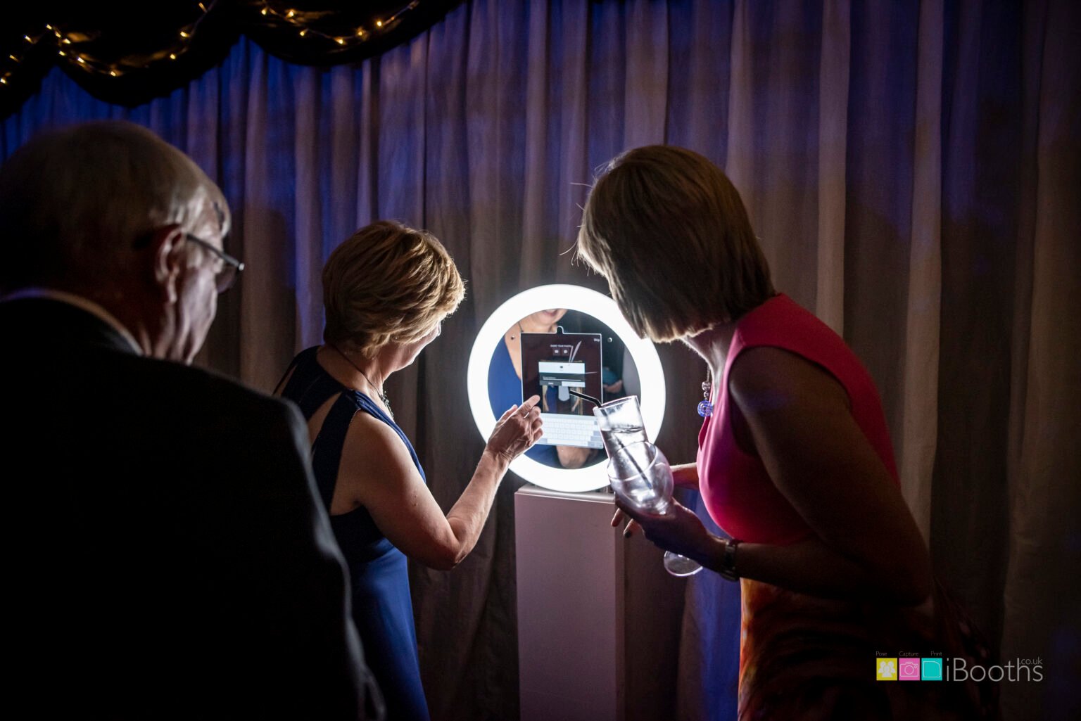 Guests using the touchscreen on the MooMuu Digital Booth at an evening event.