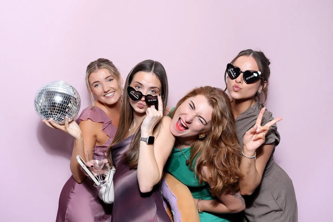 photo of a group of guests posing in front of a pink background