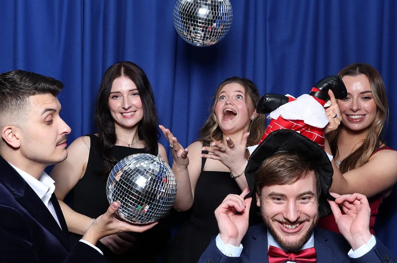 a group standing in front of a blue backdrop having fun with the photo booth
