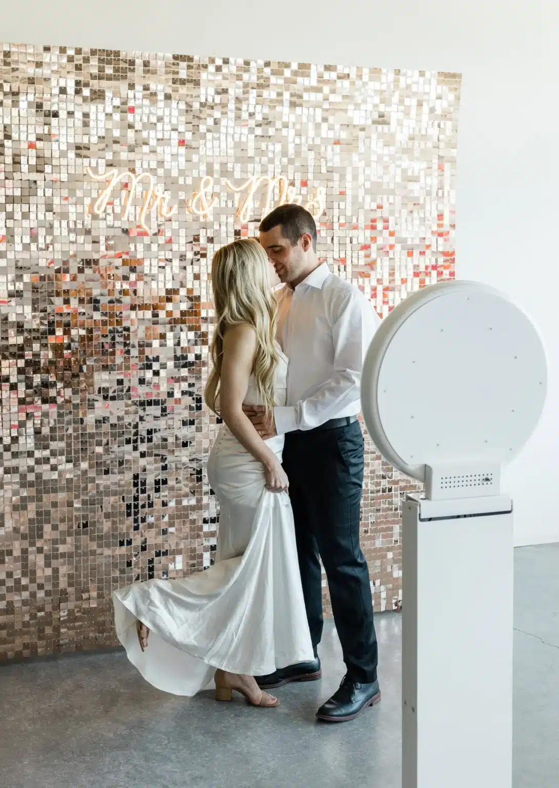 Bride and groom beside the MooMuu Digital Booth in front of a sparkling Mr & Mrs backdrop.