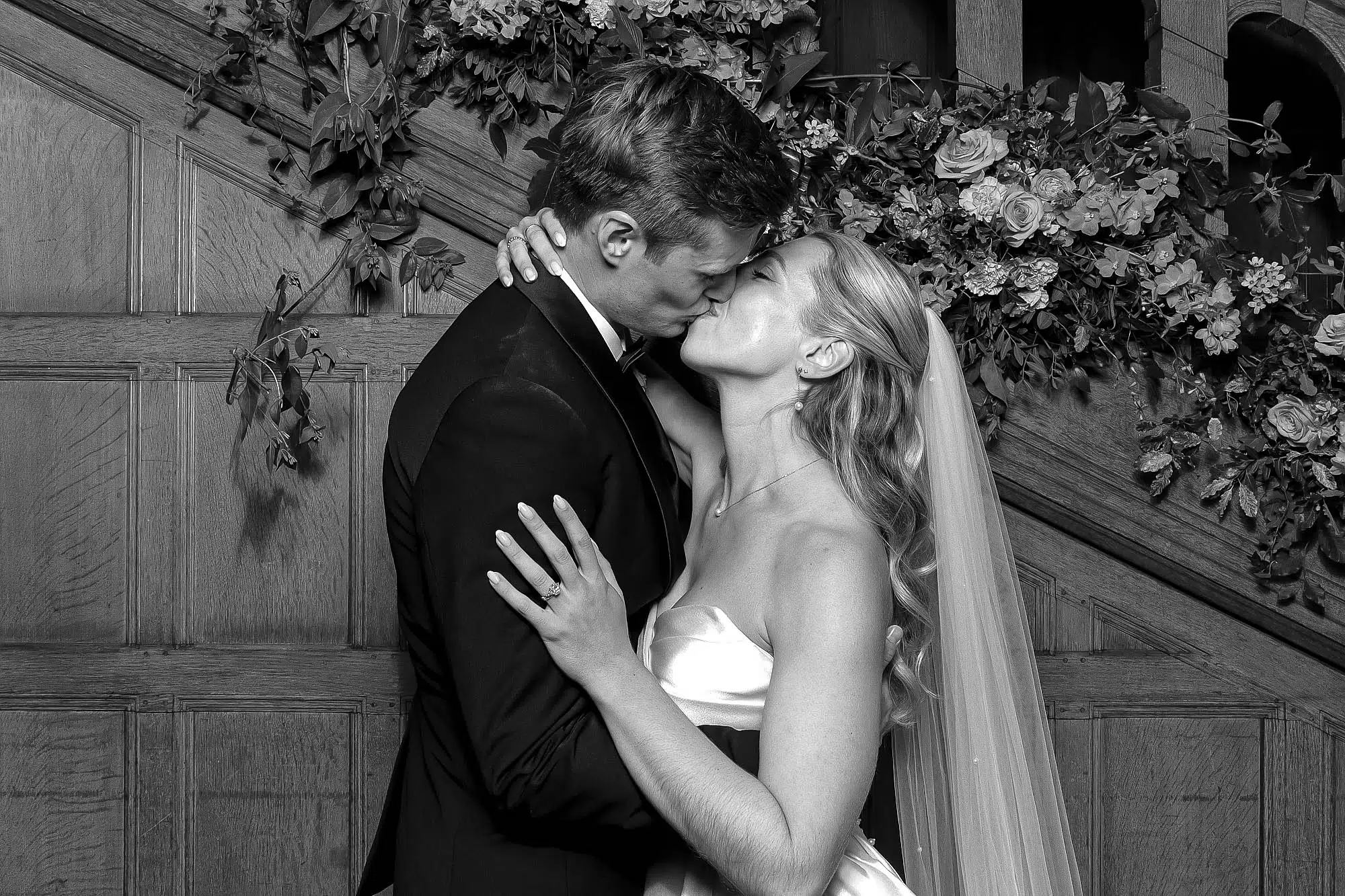 Bride and groom beside a flower-adorned wooden staircase.