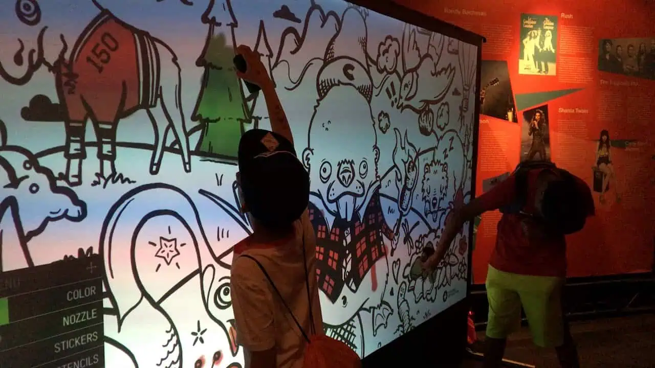Children colouring digital illustrations on a large interactive Graffiti Wall.